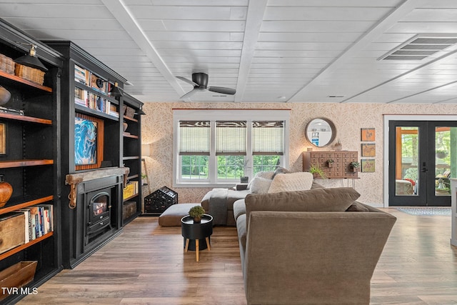 living room featuring wallpapered walls, healthy amount of natural light, ceiling fan, wood finished floors, and beam ceiling