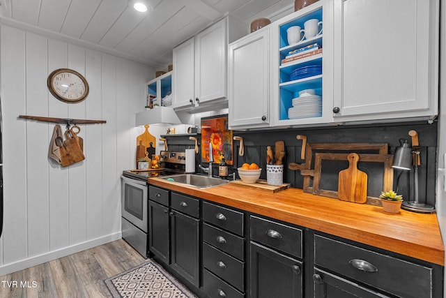 kitchen featuring electric stove, dark cabinetry, light wood-style floors, wood counters, and baseboards