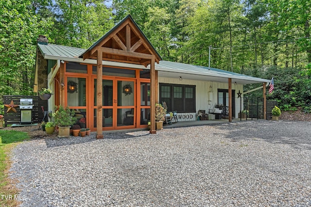 view of front of house with a chimney, metal roof, and a standing seam roof