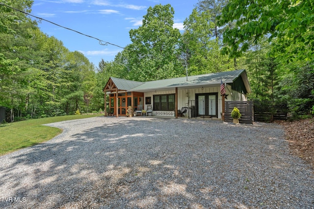 view of front of home with french doors, board and batten siding, and gravel driveway