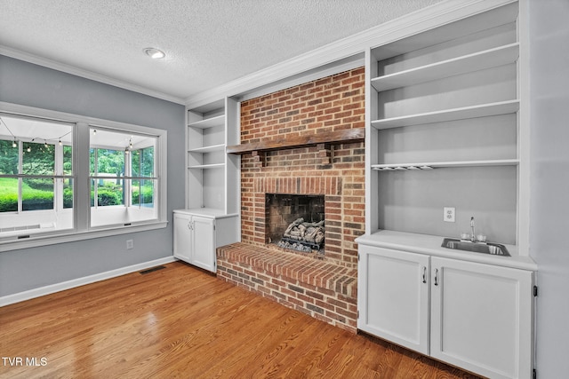 20111 Galen Dr, Abingdon, VA 24211 - unfurnished living room with a textured ceiling, crown molding, light wood-style floors, baseboards, and built in features