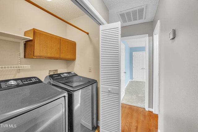 20111 Galen Dr, Abingdon, VA 24211 - laundry room featuring cabinet space, light wood-type flooring, washer and clothes dryer, and a textured ceiling