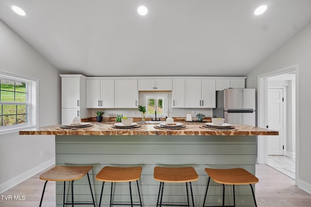 1225 Bristol View Dr, Bristol, VA 24201 - kitchen with vaulted ceiling, butcher block countertops, white cabinets, freestanding refrigerator, and a breakfast bar area
