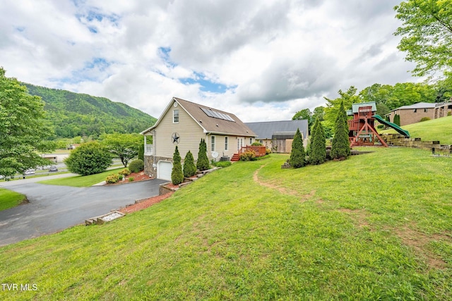 522 Crook St, Hampton, TN 37658 - view of property exterior featuring asphalt driveway, a playground, an attached garage, stone siding, and a lawn