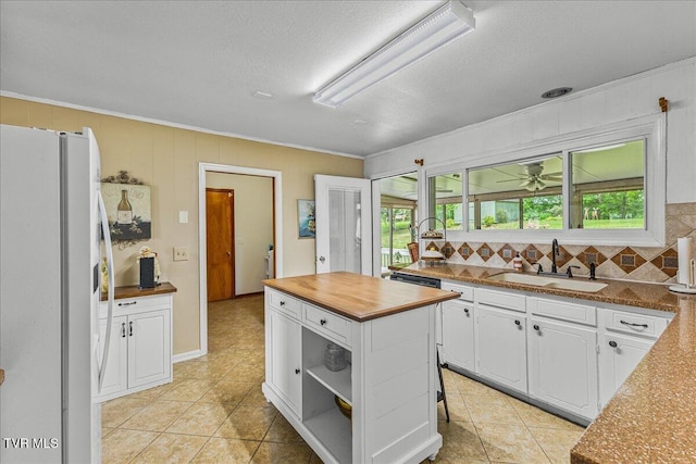 kitchen with freestanding refrigerator, a sink, butcher block countertops, white cabinetry, and plenty of natural light