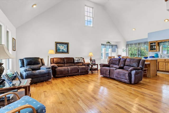 living area with high vaulted ceiling, light wood-style floors, and recessed lighting