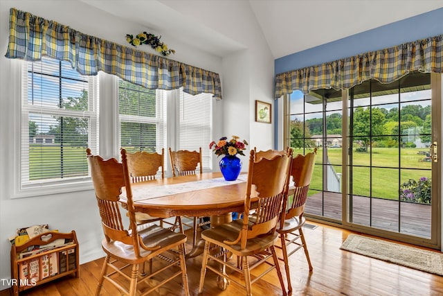 dining area with lofted ceiling, healthy amount of natural light, and wood finished floors