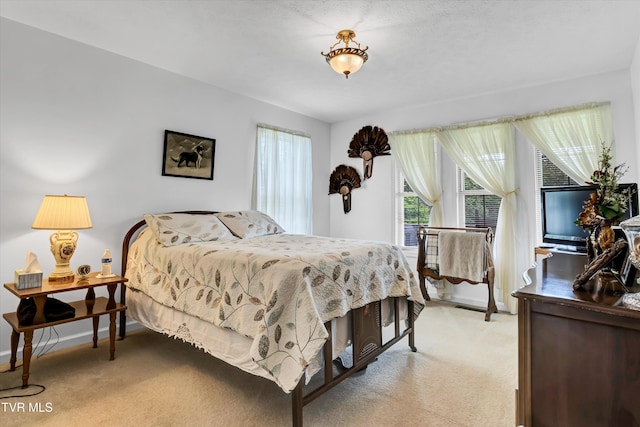 bedroom with light colored carpet and baseboards