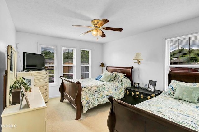 bedroom with multiple windows, light carpet, a ceiling fan, and baseboards