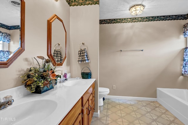full bathroom featuring toilet, a bath, a textured ceiling, double vanity, and baseboards