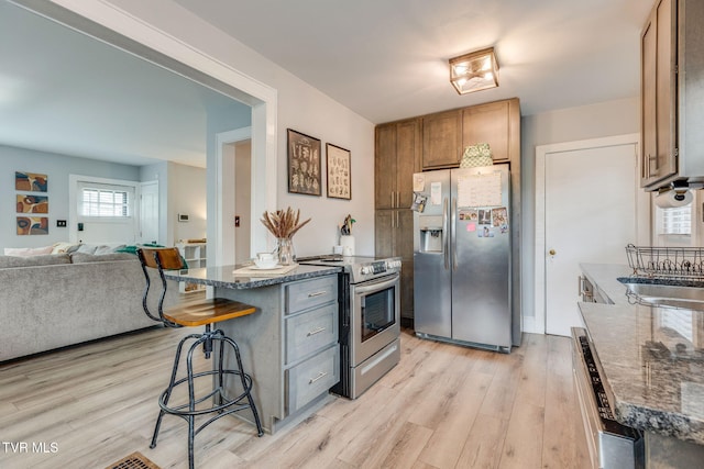 1462 Valley St, Kingsport, TN 37660 - kitchen featuring appliances with stainless steel finishes, light wood-style floors, a kitchen bar, a sink, and open floor plan