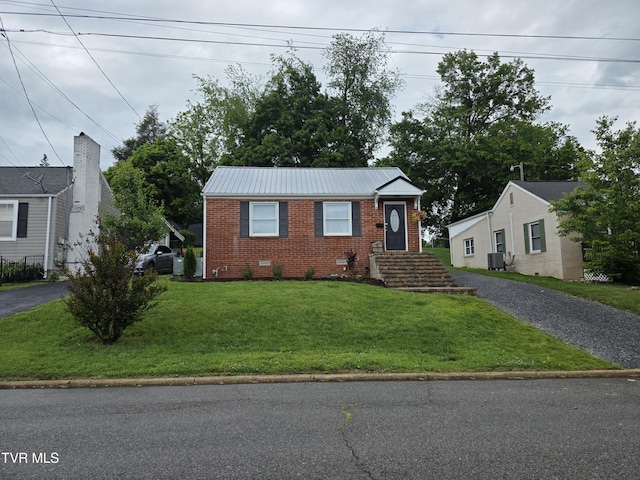 1317 Newton St, Bristol, VA 24201 - view of front of property with brick siding, central air condition unit, asphalt driveway, a front lawn, and metal roof
