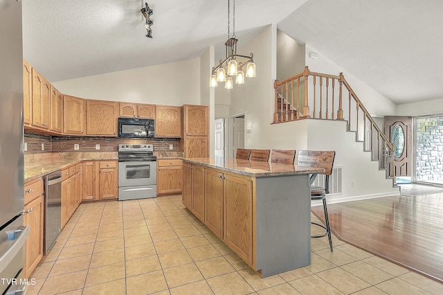 476 Sportsman Dock Rd, Piney Flats, TN 37686 - kitchen with appliances with stainless steel finishes, a kitchen island, tasteful backsplash, light tile patterned floors, and light stone countertops