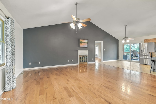 476 Sportsman Dock Rd, Piney Flats, TN 37686 - unfurnished living room with a ceiling fan, high vaulted ceiling, light wood-style flooring, baseboards, and a glass covered fireplace