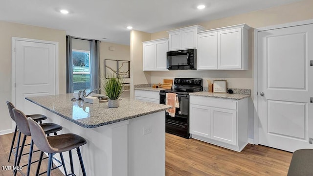1513 Fox Meadows Cir, Bluff City, TN 37618 - kitchen featuring black appliances, a breakfast bar area, light wood-style floors, a center island with sink, and recessed lighting