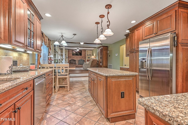 2309 Oxford Ct, Kingsport, TN 37660 - kitchen featuring appliances with stainless steel finishes, brown cabinetry, a center island, decorative backsplash, and recessed lighting