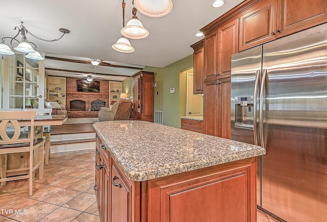 2309 Oxford Ct, Kingsport, TN 37660 - kitchen with stainless steel refrigerator with ice dispenser, a fireplace, a kitchen island, brown cabinetry, and light tile patterned floors