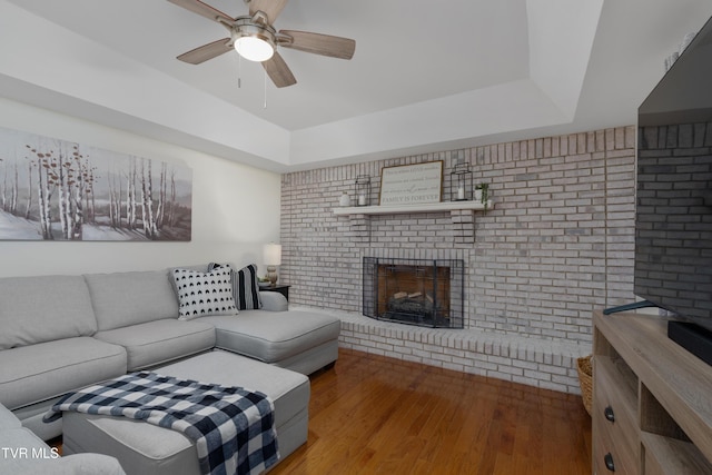 821 Regency Dr, Johnson City, TN 37604 - living room featuring a raised ceiling, wood finished floors, a brick fireplace, brick wall, and a ceiling fan
