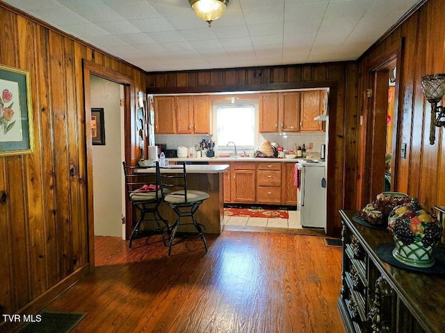 11811 Central St, Coeburn, VA 24230 - kitchen featuring white range with electric stovetop, wood walls, light wood-type flooring, a breakfast bar, and brown cabinetry
