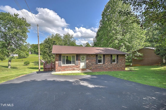 view of front facade with brick siding, a front lawn, and driveway
