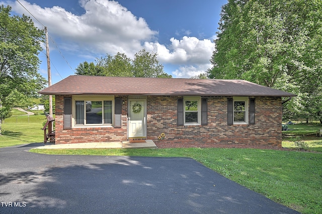 view of front of house featuring brick siding, a front lawn, and a shingled roof