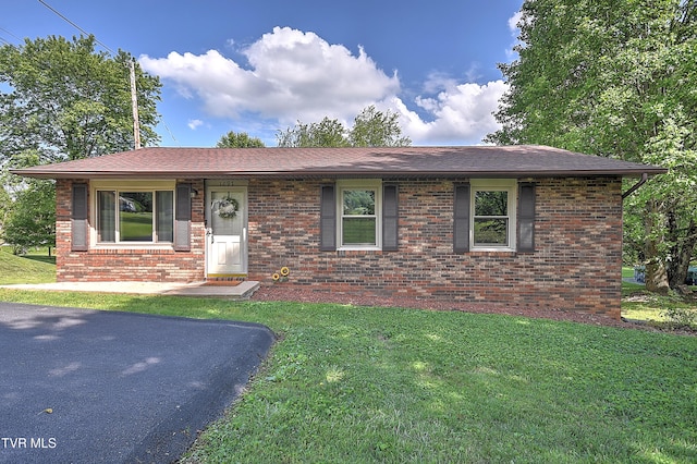 view of front of house with a front yard, brick siding, and a shingled roof