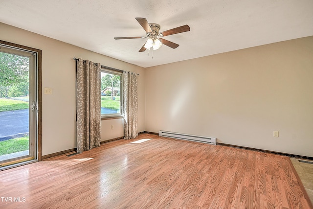 spare room with baseboard heating, light wood-type flooring, ceiling fan, and baseboards
