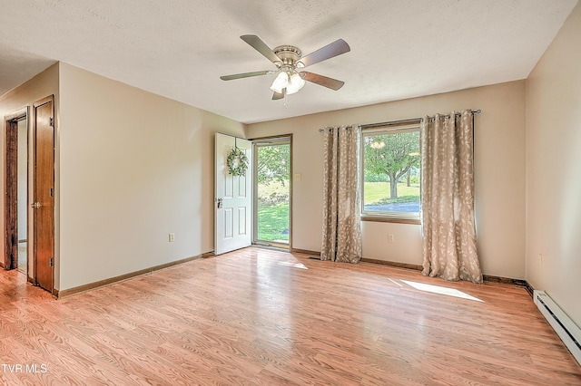 spare room featuring a baseboard radiator, light wood finished floors, ceiling fan, baseboards, and a textured ceiling