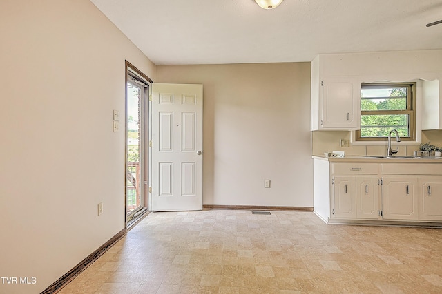 kitchen with baseboards, a sink, white cabinetry, and light countertops