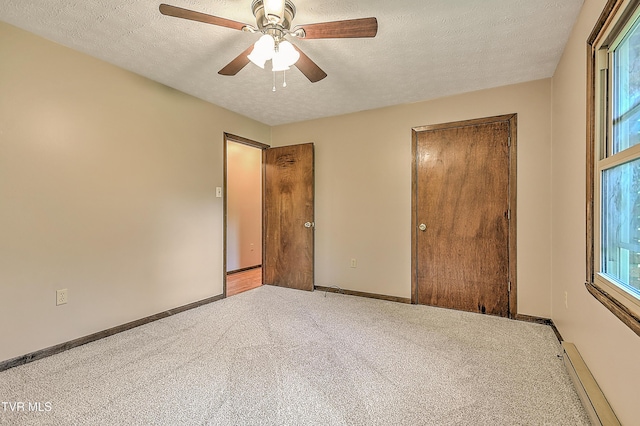 unfurnished bedroom featuring a baseboard radiator, carpet flooring, baseboards, a textured ceiling, and a closet
