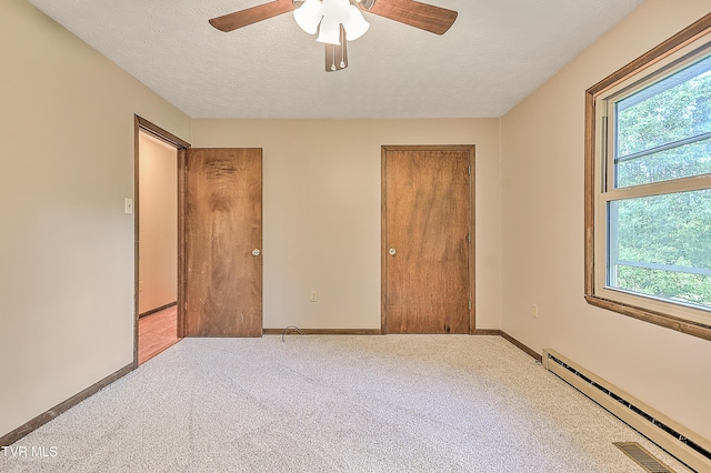 unfurnished bedroom with baseboard heating, multiple windows, carpet floors, and a textured ceiling