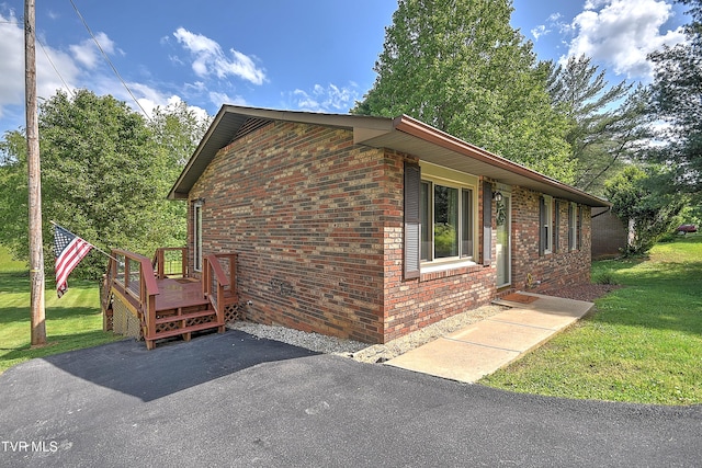 view of side of home featuring a yard, brick siding, and a deck