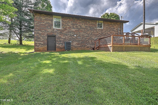 rear view of property featuring a wooden deck, brick siding, central AC unit, and a lawn
