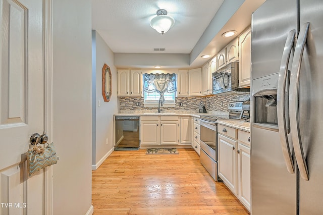 204 E Mountain View Rd # 20, Johnson City, TN 37601 - kitchen featuring black appliances, backsplash, a sink, light wood-type flooring, and baseboards