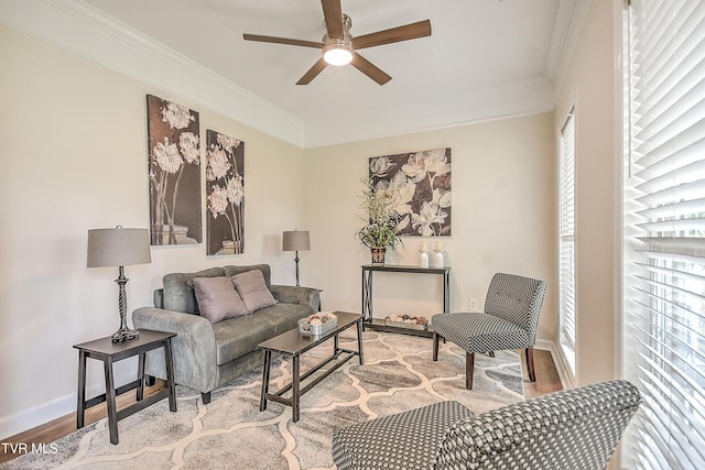 living room featuring wood finished floors, ornamental molding, a ceiling fan, and baseboards