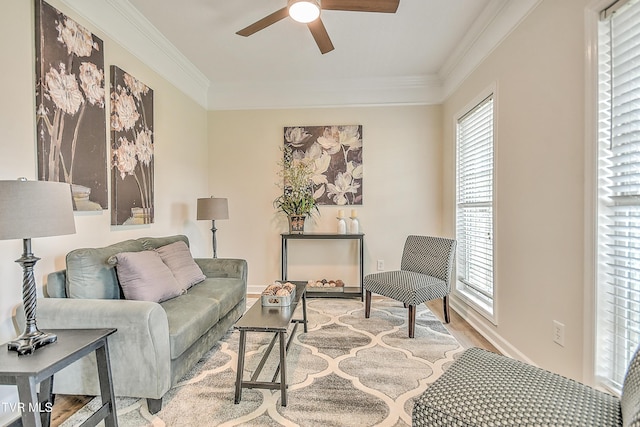 living area with a ceiling fan, wood finished floors, ornamental molding, and baseboards
