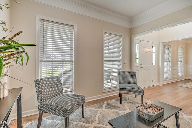 sitting room featuring ornamental molding, light wood-type flooring, and baseboards