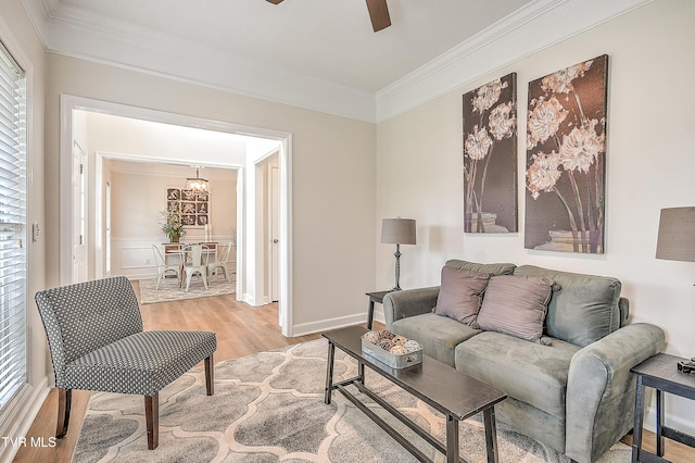 living area featuring ornamental molding, a ceiling fan, light wood-type flooring, plenty of natural light, and a chandelier