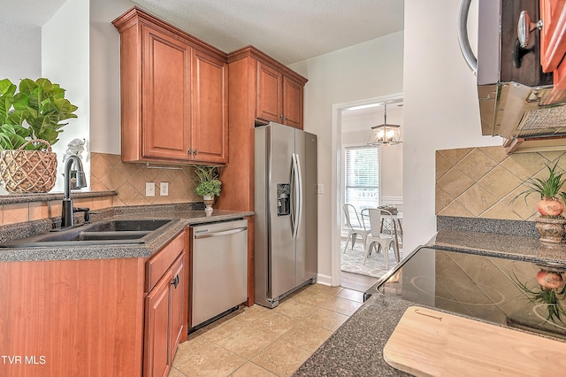 kitchen featuring stainless steel appliances, a sink, dark countertops, decorative backsplash, and brown cabinets