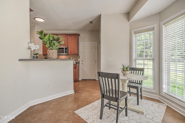dining room with baseboards, light tile patterned flooring, and a textured ceiling