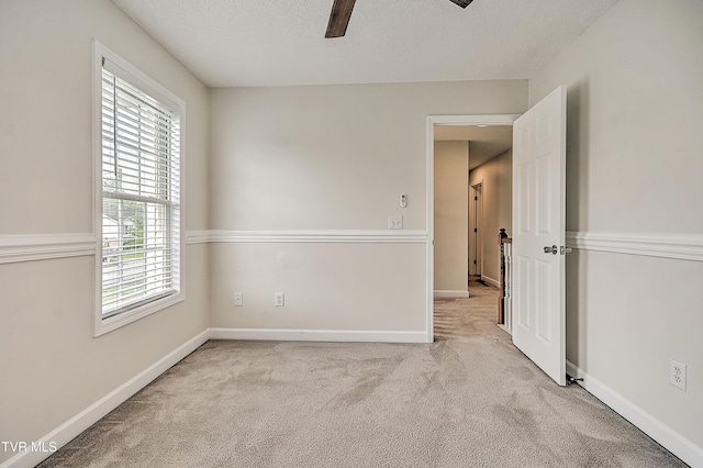 spare room featuring ceiling fan, carpet flooring, a textured ceiling, and baseboards