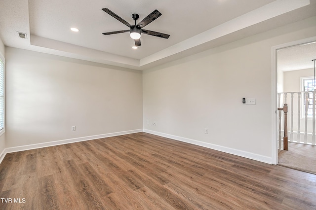 unfurnished room with ceiling fan, wood finished floors, baseboards, recessed lighting, and a raised ceiling