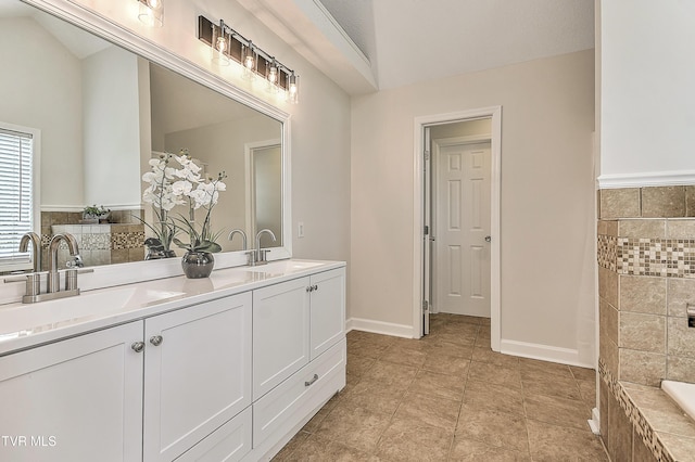 full bath featuring double vanity, tiled bath, baseboards, and vaulted ceiling