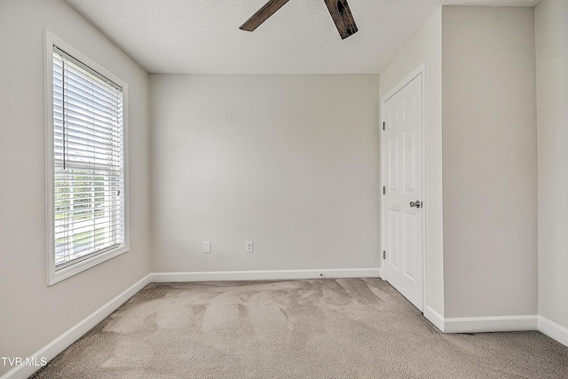 carpeted spare room with ceiling fan, baseboards, and a textured ceiling