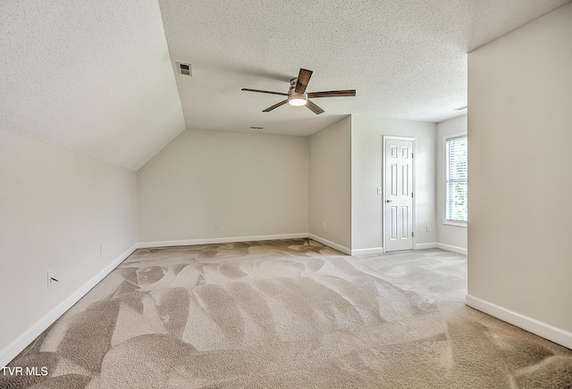 bonus room featuring ceiling fan, a textured ceiling, carpet floors, baseboards, and vaulted ceiling