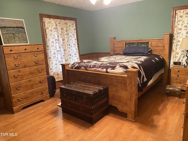 203 Oak Ln, Johnson City, TN 37604 - bedroom featuring a wainscoted wall, light wood finished floors, a textured ceiling, and wood walls