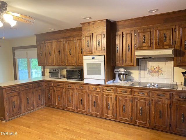 203 Oak Ln, Johnson City, TN 37604 - kitchen with white oven, black electric stovetop, under cabinet range hood, a ceiling fan, and light wood finished floors