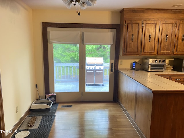 203 Oak Ln, Johnson City, TN 37604 - kitchen with tile counters, healthy amount of natural light, brown cabinetry, and light wood-style flooring