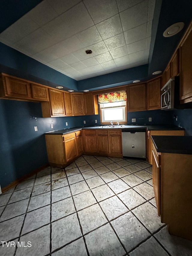 405 W Main St, Saltville, VA 24370 - kitchen with appliances with stainless steel finishes, brown cabinetry, light tile patterned floors, dark countertops, and a sink