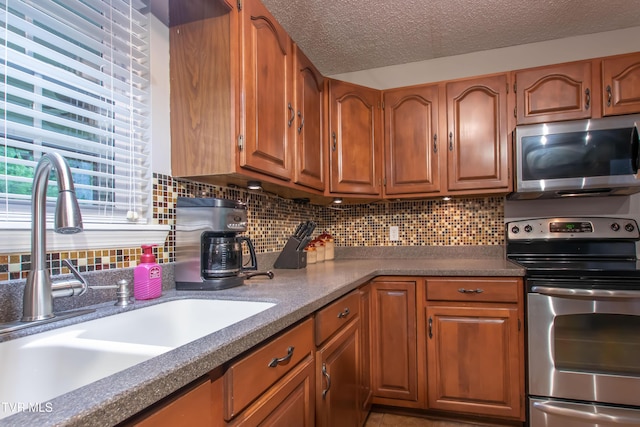 3493 Weaver Pike, Bristol, TN 37620 - kitchen featuring appliances with stainless steel finishes, a sink, brown cabinets, decorative backsplash, and a textured ceiling